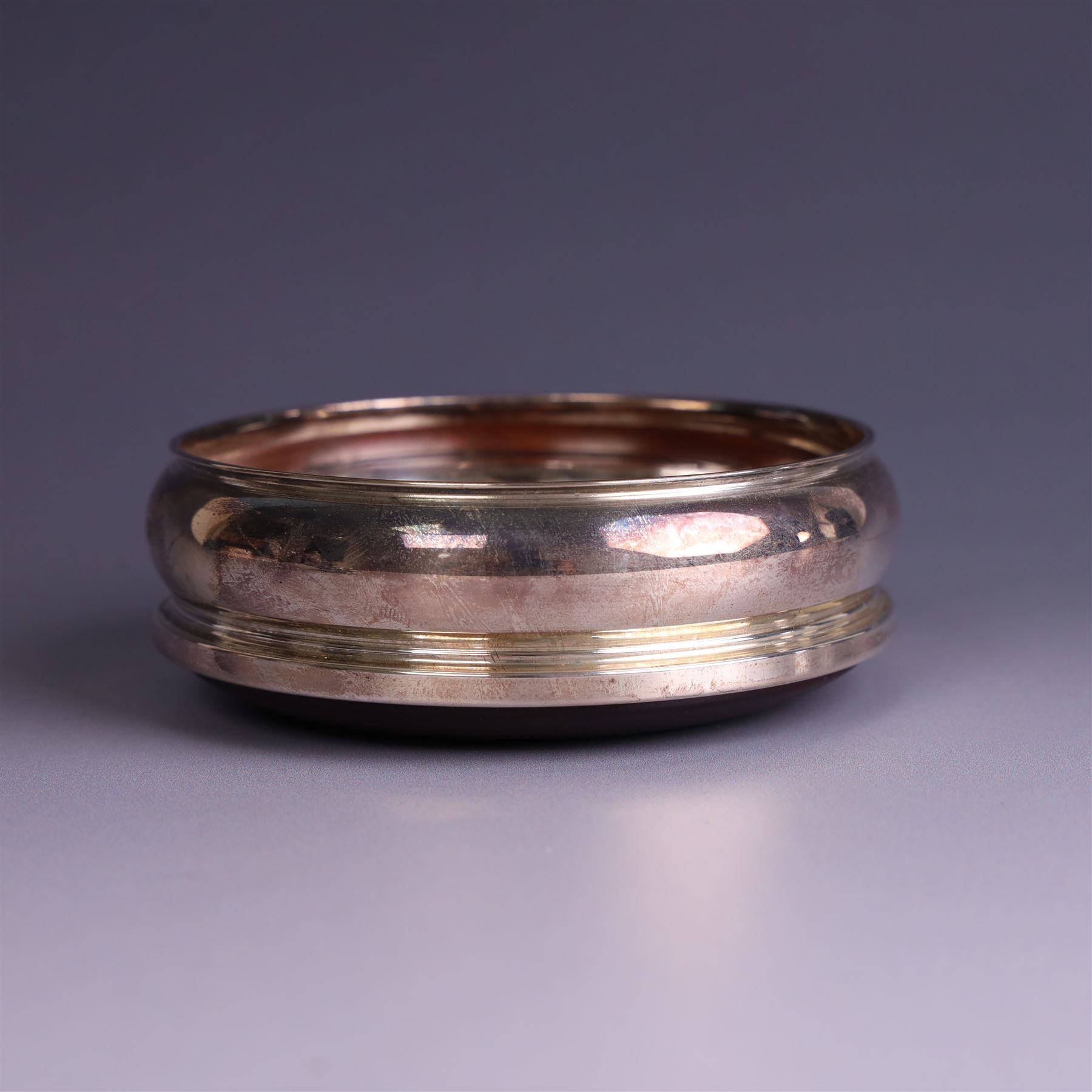 Modern silver mounted bottle coaster, with turned wooden base, hallmarked Carrs of Sheffield Ltd, Sheffield 2003 and a Victorian silver inkwell stand, hallmarks worn and indistinct, coaster D10cm