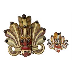 Sri Lankan Cobra mask depicting the demon Naga Raksha, together with a smaller example, largest H46cm