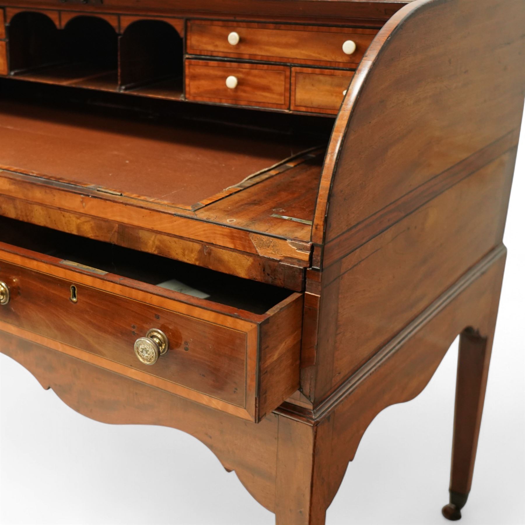 George III mahogany cylinder front writing desk, the hinged tambour enclosing pigeonholes and drawers with bone handles, sliding writing surface with leather inset, three frieze drawers below, on square tapering legs with brass caps and castors