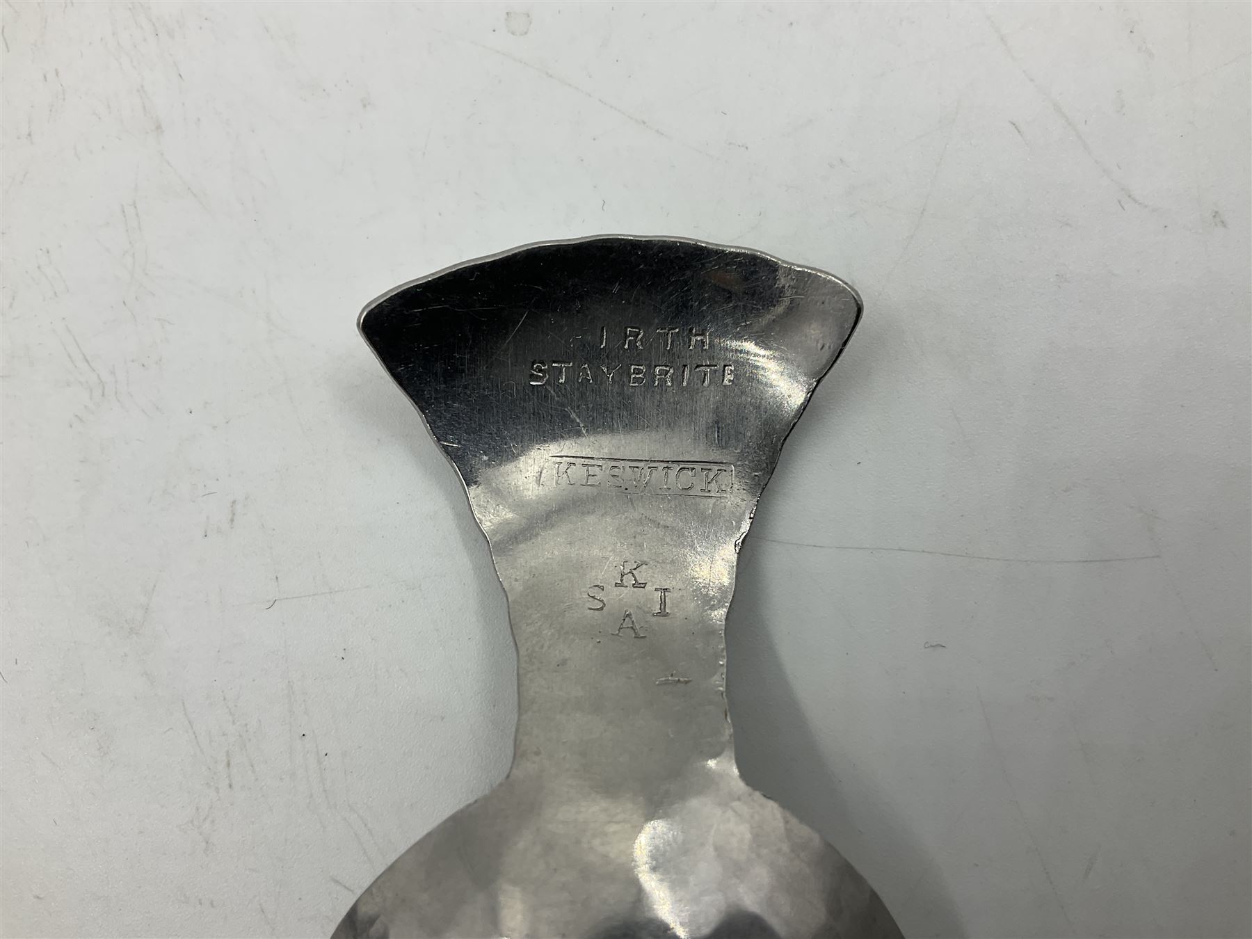 Keswick School of Industrial Arts (KSIA), Arts and Crafts hammered steel Staybrite caddy spoon, L6.5cm, and dish with engraved fern decoration to centre, D11.5cm, both with impressed marks beneath