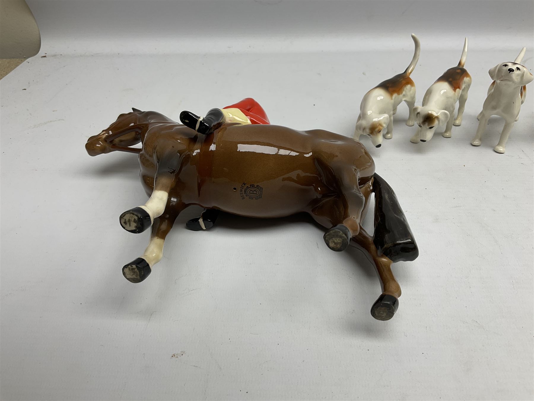 Beswick hunting group, comprising huntswoman on grey horse no 1730, huntsman on brown horse no 1501, two seated fox figures no 1748 and seven fox hounds, all with printed marks beneath (11)