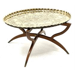 Mid 20th century coffee table, oval brass top with engraved floral decoration, on folding teak angular base