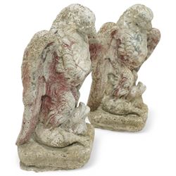Pair of early 20th century painted stoneware eagle figures, modelled with wings partially spread and talons gripping prey, on a stone plinth