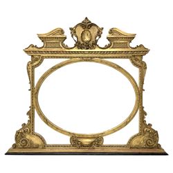 19th century gilt wood and gesso overmantel mirror, the shaped swan neck pediment with floral swag and shell decoration, oval central bevelled mirror plate with a reed and leaf moulded surround, segmented corner bevelled panels, shaped corner brackets with acanthus scroll decoration, small central shelf with gadrooned underside, on stepped gilt and ebonised moulded base