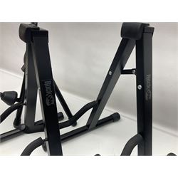 Four folding tubular guitar stands, two by RockJam; and folding tubular saxophone stand (5)