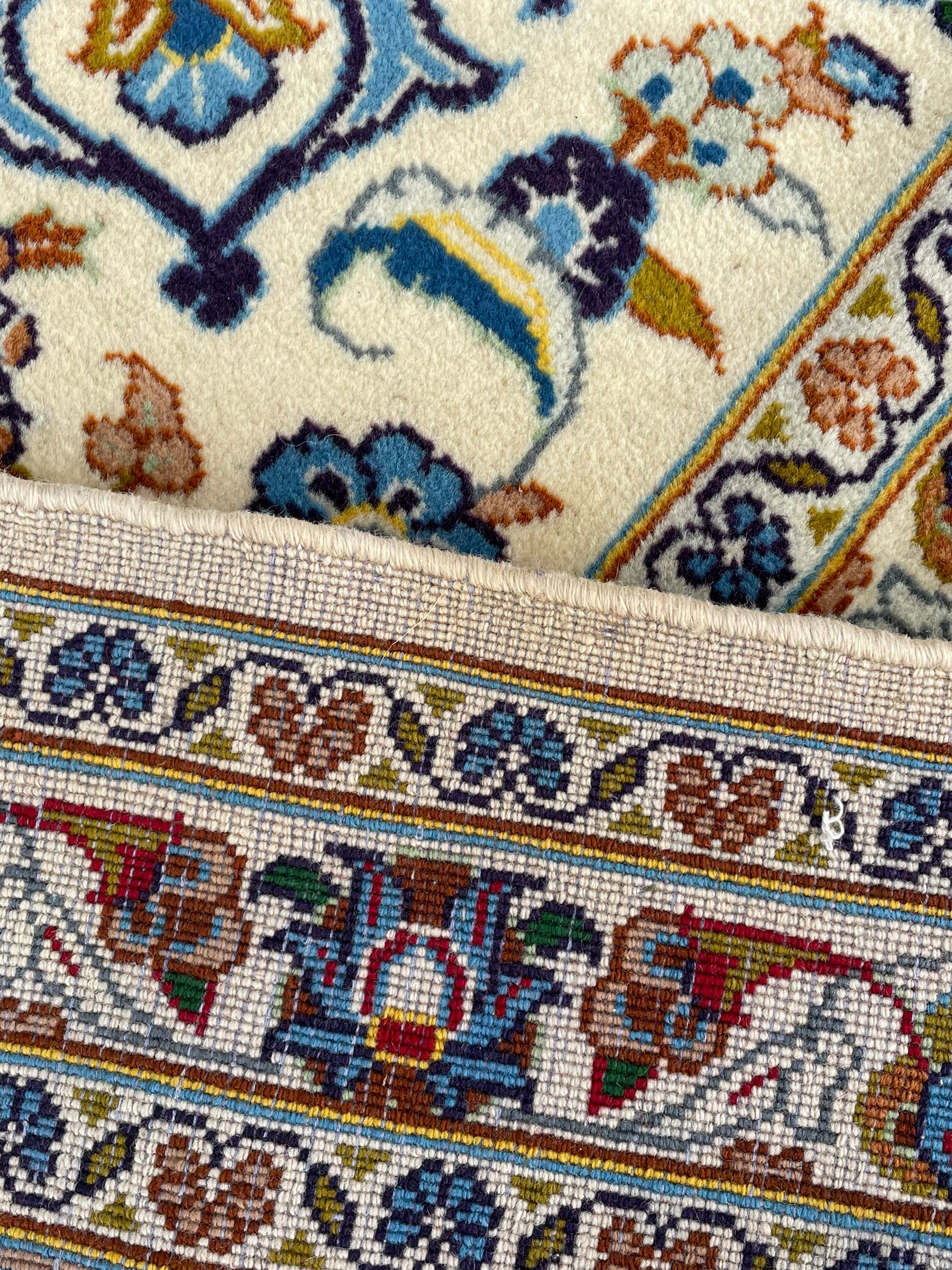 Persian Kashan ivory ground carpet, the interlaced foliate medallion surrounded by trailing plant motifs interlaced with scrolls, the guarded border with repeating stylised flower heads