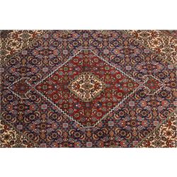 North West Persian Tabriz hand-knotted rug, ivory field with a central lozenge medallion in deep indigo and madder red, enclosing a inner reserve with stylized floral motifs, spandrels with angular floral sprays, main border of repeating floral vinery and palmettes, framed by multiple guard borders, with cotton fringe ends