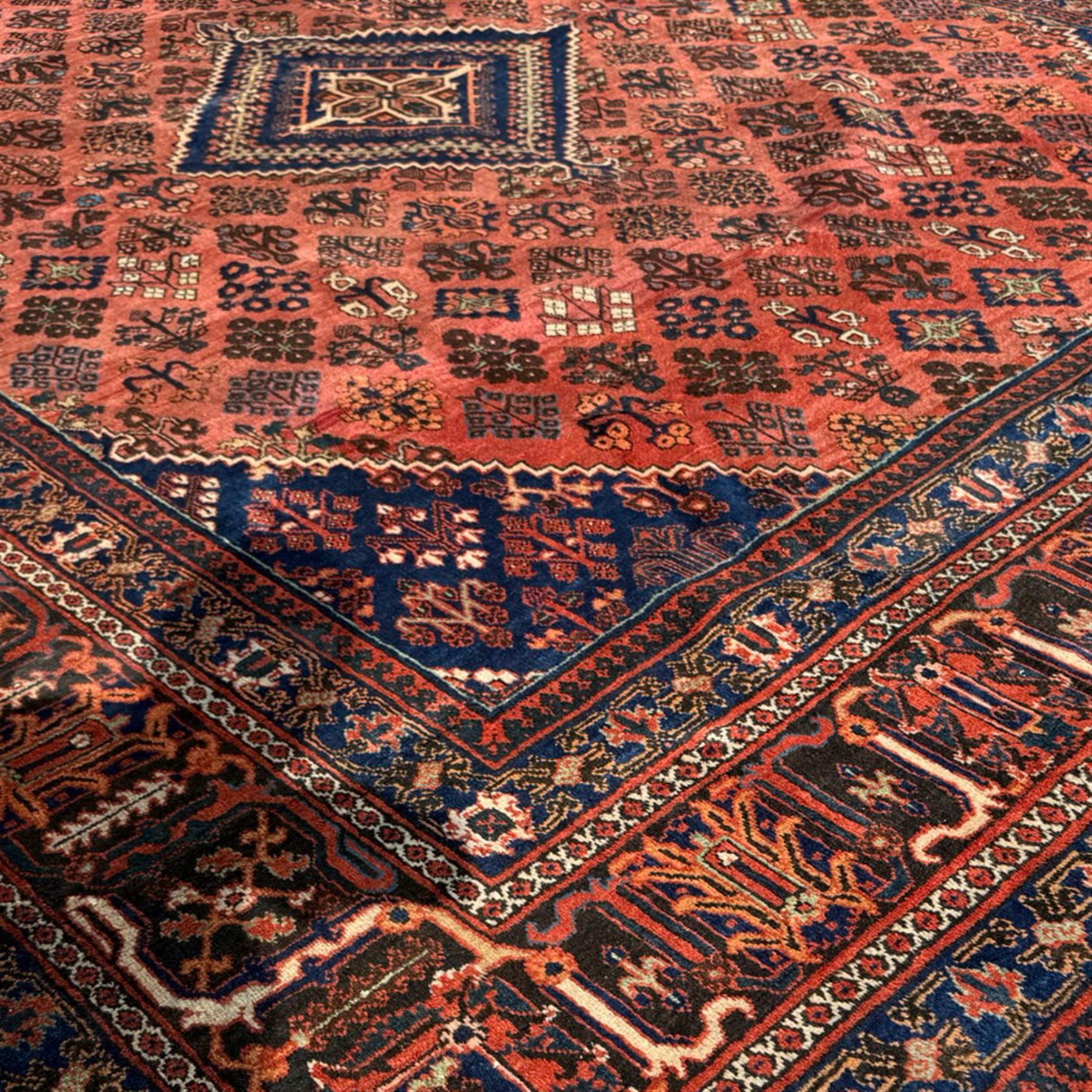Joshgan Persian wool rug, with diamond-framed medallion, on a deep red field filled with geometric-shaped floral motifs and indigo-filled spandrels 