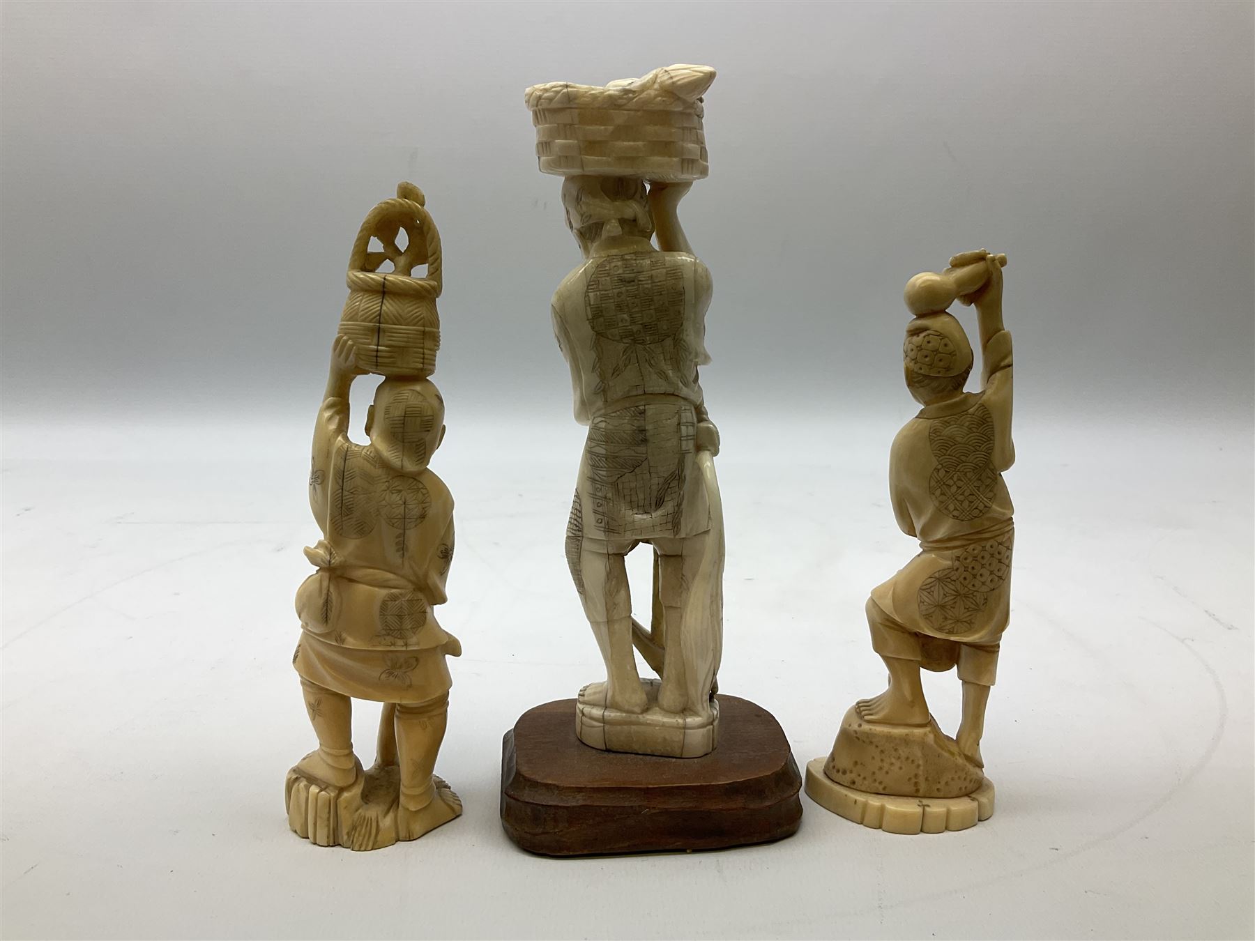 Three Japanese Tokyo School ivory figure, 19th century, comprising of man standing holding double gordes, man holding a flower with a basket on his head and a man with an adze and a basket with a frog in, tallest example H19cm, 