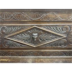 Late 19th century heavily carved oak monks bench, scroll carved pediment with central anthemion motif, panelled back with lozenge and carved green man mask, down swept arms in form of recumbent lions flanking hinged box seat, panelled base carved with masks and scrolls on moulded skirt