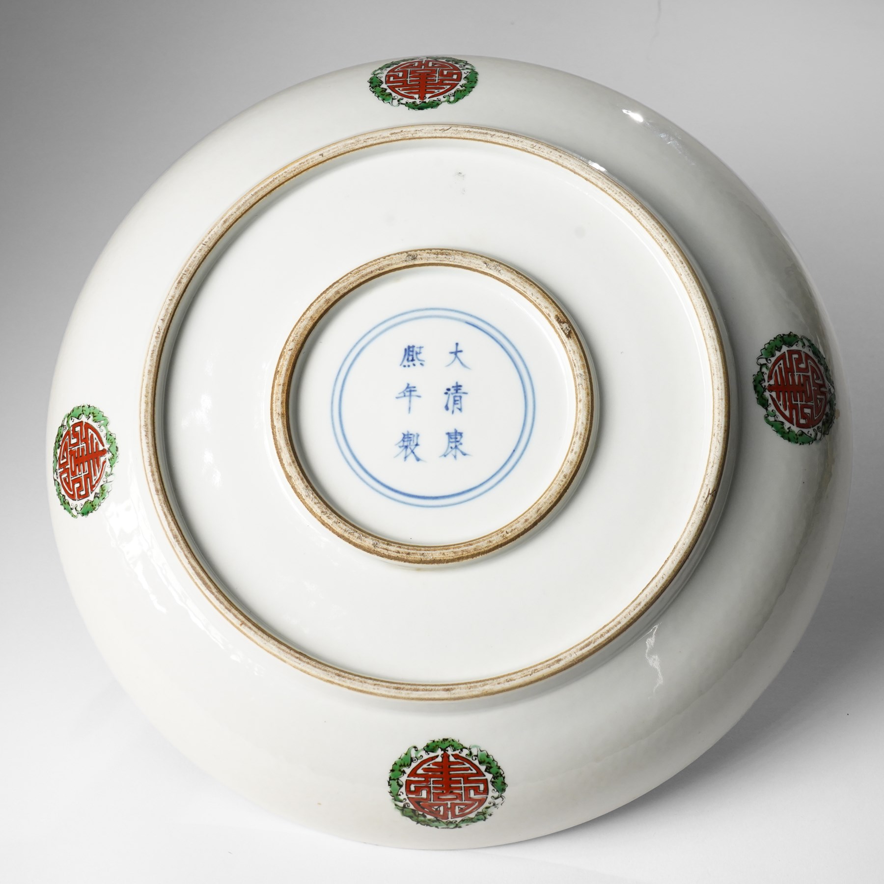Chinese charger, decorated in blue, green and red enamels with a four clawed dragon chasing the flaming pearl amidst waves and flower heads, the rim with border of alternating reserves of auspicious emblems and flower scrolls, bearing apocryphal Kangxi mark beneath, D38cm 

