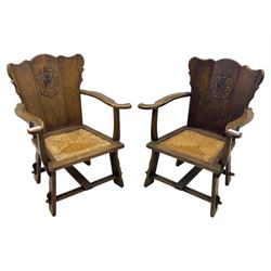 Pair of Arts and Crafts oak armchairs each with shaped backrest centred by polychrome painted crest, rush seat over straight square legs united by shaped central stretcher