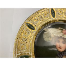 Late 19th century cabinet plate in the manner of Vienna, finely painted with quarter length portrait of the Queen of the Roses, signed Wagner, within elaborate gilt foliate scroll panelled border on white ground interspersed with raised green oval motifs painted to mimic marble, with impressed and red beehive marks, titled Königin der Rosen no 10171 and stamped Germany, D23.5cm