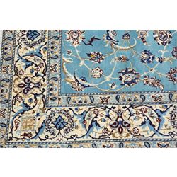 Central Persian Nain hand-knotted carpet, soft sky blue ground with central cusped medallion of radiating palmette form, issuing scrolling vine work, arabesques, and delicate floral sprays, spandrels of conforming design, main border of ivory ground decorated with scrolling vine work palmettes and stylized floral motifs, flanked by narrow guard stripes, with cotton fringe ends 