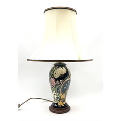 A Moorcroft table lamp, of baluster form, decorated in the Golden Lily pattern upon a dark blue ground, with accompanying cream shade of lobed form, with piped detail, overall H59cm.