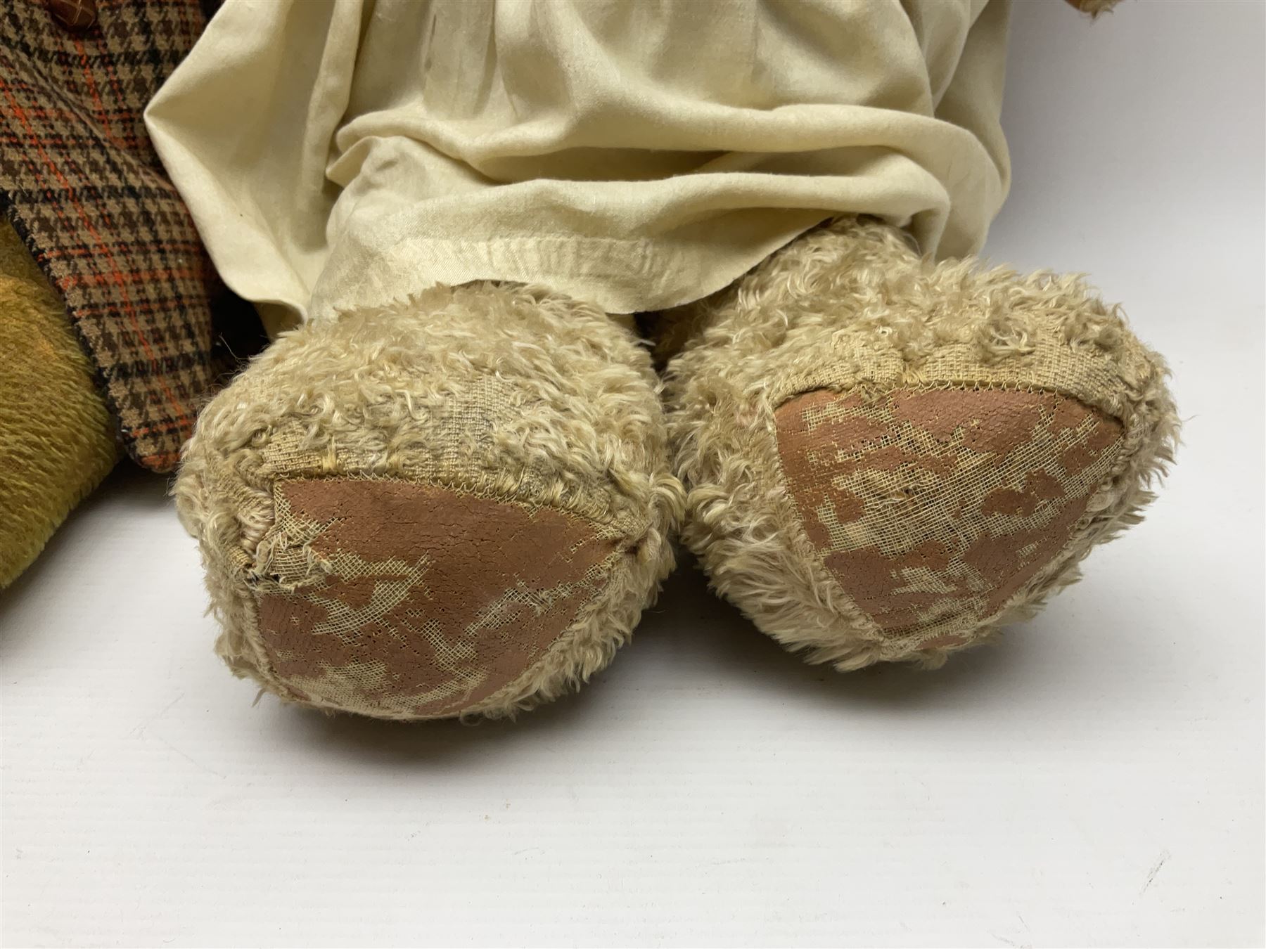 Two early 20th century straw filled jointed teddy bears, first example wearing a tweed jacket bearing Geoffrey Saville label, with leather padded paws and ears, horizontally stitched nose and humpback; second example with applied eyes, vertically stitched nose and faux leather paw pads, both with growler mechanisms, tallest H74cm 