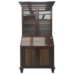 Early 19th century figured mahogany bureau bookcase, projecting splay moulded cornice over three adjustable shelves enclosed by two glazed doors, fall front revealing pigeonholes, cupboard and drawers, pull-out strays with scroll carved terminals, double cupboard with two panelled doors, on turned feet 