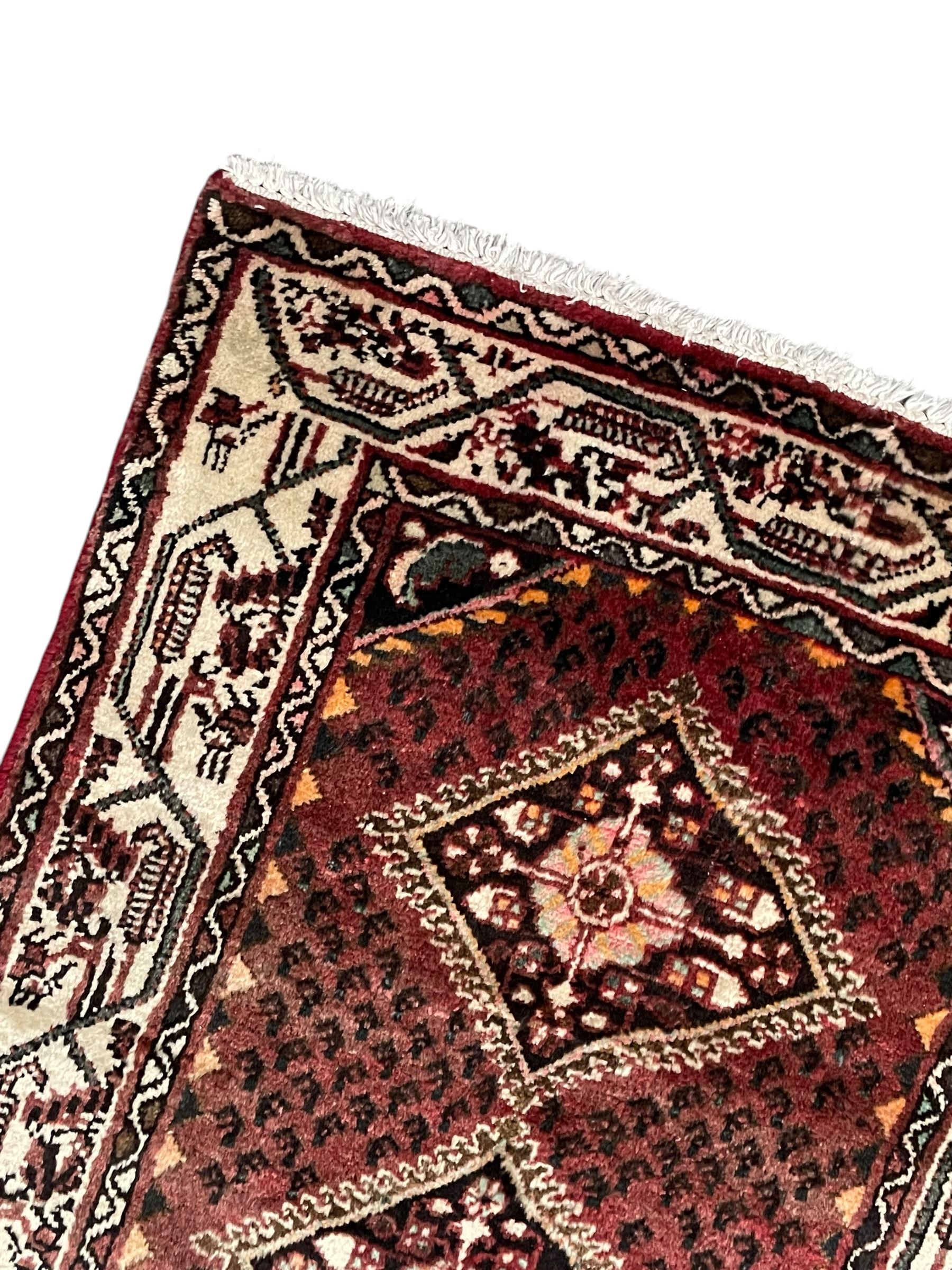 Persian Baluch red ground runner, seven lozenge medallions each decorated with stylised floral motifs, ivory border decorated with trailing pattern and Boteh motifs, within geometric guard stripes 