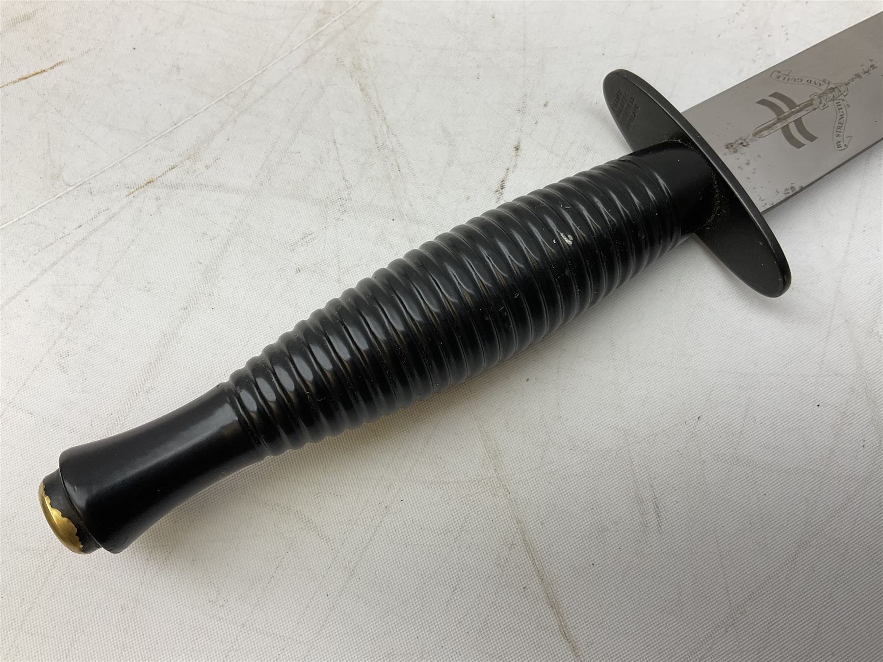 Gulf War period commando knife with 17cm double-edged steel blade etched with the crest and motto 'By Strength and Guile', blackened cross-piece and grip; in webbing scabbard L31cm overall