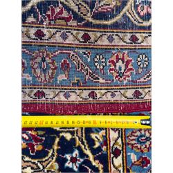 Northeastern Persian Meshed hand-knotted carpet, madder red field with an all-over design of scrolling vines, palmettes, and rosettes, within a dark blue border of palmettes and arabesques 
