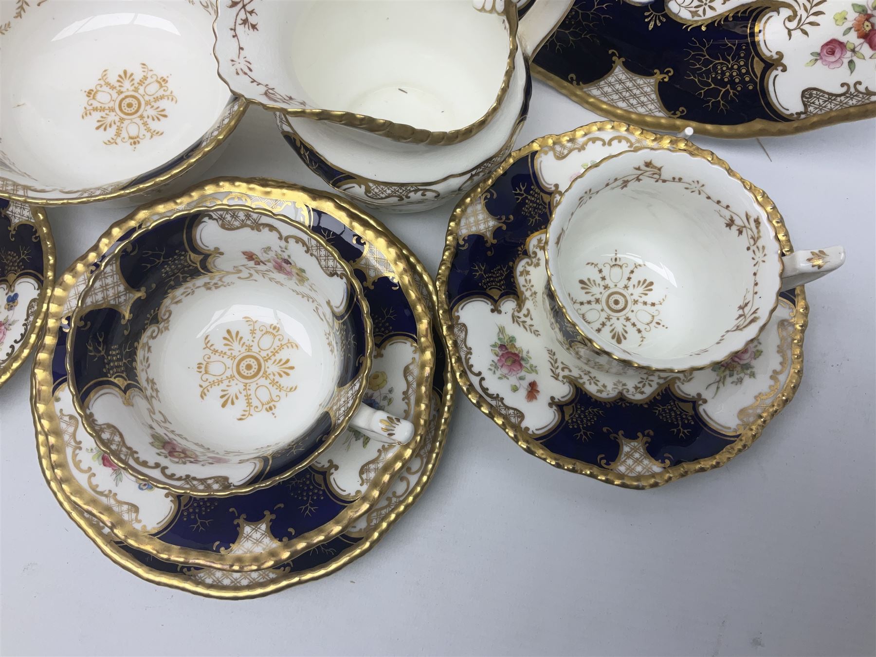 Coalport cobalt blue batwing pattern tea wares, decorated with finely enamelled floral sprays within gilt reserves, comprising teacup trio, coffee can and saucer and other cup and saucer, twin handled cake plate, milk jug and open sucrier, and circular plate retailed by T. Goode & Co London, pattern no Y2665,  all with green Coalport AD 1750 marks beneath, largest W26cm (11)