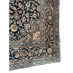 Persian Kashan indigo ground rug, the rosette medallion decorated with projecting palmettes, on a field of swirling leafy branches and decorated with further palmettes, the scrolling border with repeating stylised plant motifs, within floral pattern guard stripes
