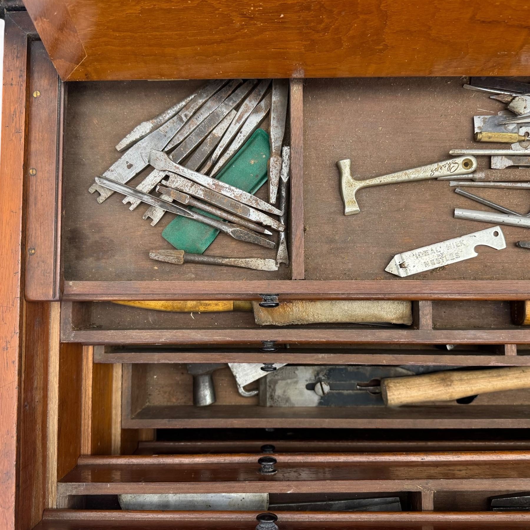 20th century black painted camphorwood lined tool chest, rectangular hinged lid over moulded edge, black painted exterior with iron straps and carry handles, the interior fitted with sliding lidded trays and drawers with turned handles, containing an assortment of hand tools