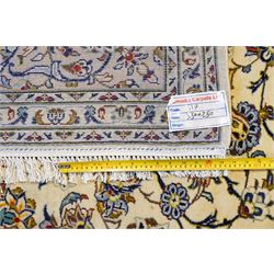 Central Persian Kashan hand-knotted carpet, ivory field decorated with an all-over scrolling floral vine design incorporating stylized palmettes, rosettes, and foliate sprays in the Shah-Abassi style enclosed by a series of floral vine borders and multiple narrow guard stripes, cotton fringe ends 