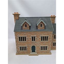 1:24 scale stone effect three-storey cottage dolls house, with green arched door and lattice effect windows, decorated to the interior with wooden floors, wired lighting and fire places, H45cm, W57cm, D26cm