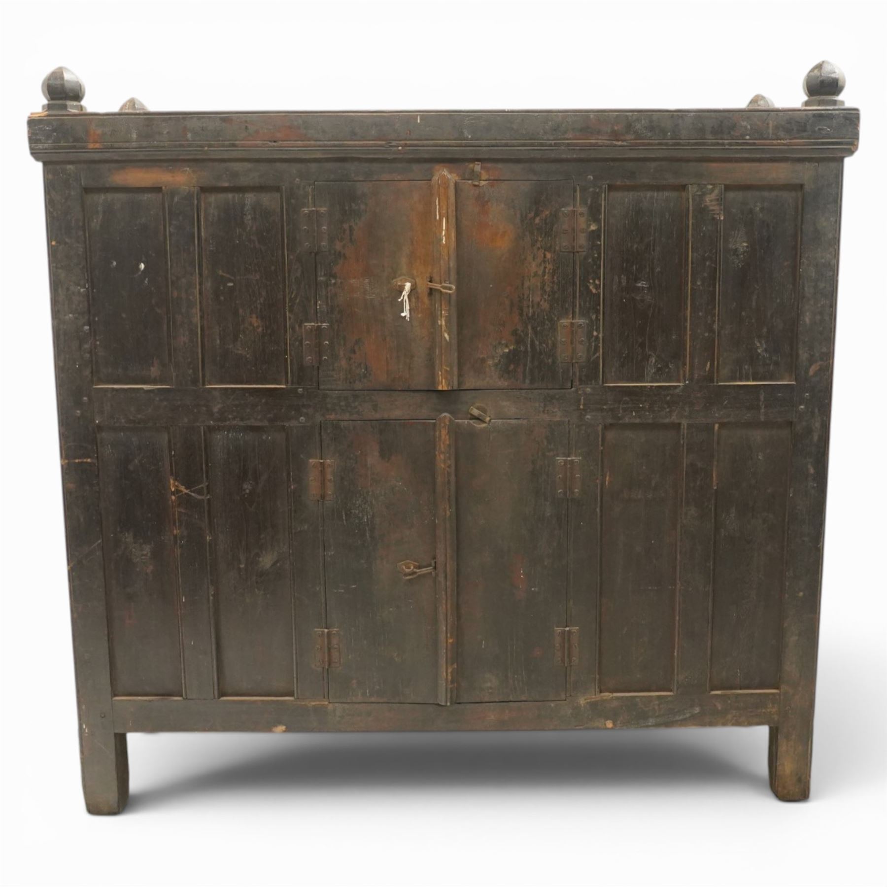 19th century oak hutch cupboard, plank top with moulded cornice and turned finials, panelled front enclosed by two tiers of central double doors with iron hinges and wooden latches, flanked by fixed fielded panels, on stile supports