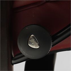 Ekornes - Stressless reclining armchair and matching footstool, upholstered in oxblood leather with padded headrest and segmented back cushion, shaped armrests with exposed adjustment handles, raised on stained laminated beech circular swivel base, the conforming stool on matching ring base