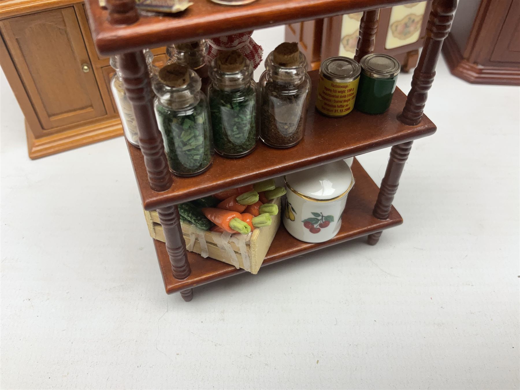 Collection of kitchen and bedroom dolls house furniture, to include two units housing Reutter, Germany ceramic plates, tea wares and accessors comprising one example with a Belfast sink with various pots and pans and jars, the second housing various baking equipment, two dressers, baking table, shelf unit housing various jars of herbs and basket of produce, fridge, and lace and jacquard bedroom suite including bed, pair of bedside tables, dressing table and ottoman