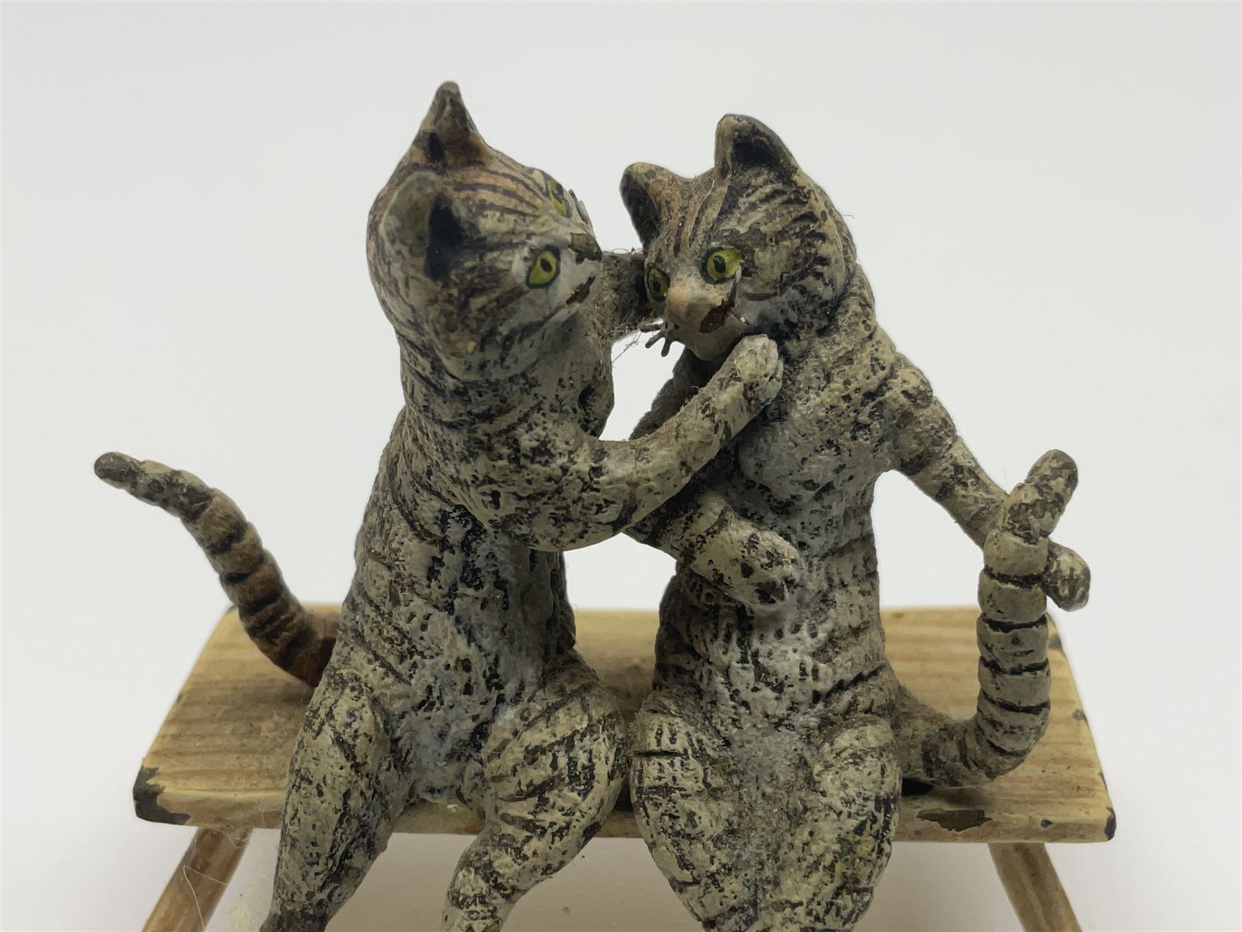 After Bergmann, two cold painted bronze figures, the first modelled as two cats on a bench hugging, the second a cat caning a kitten