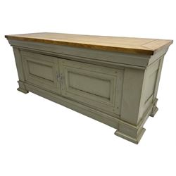 Painted oak side cupboard or television stand, rectangular oak top over two panelled cupboard doors, on stepped plinth base with compressed block feet, in washed laurel green paint and waxed finish