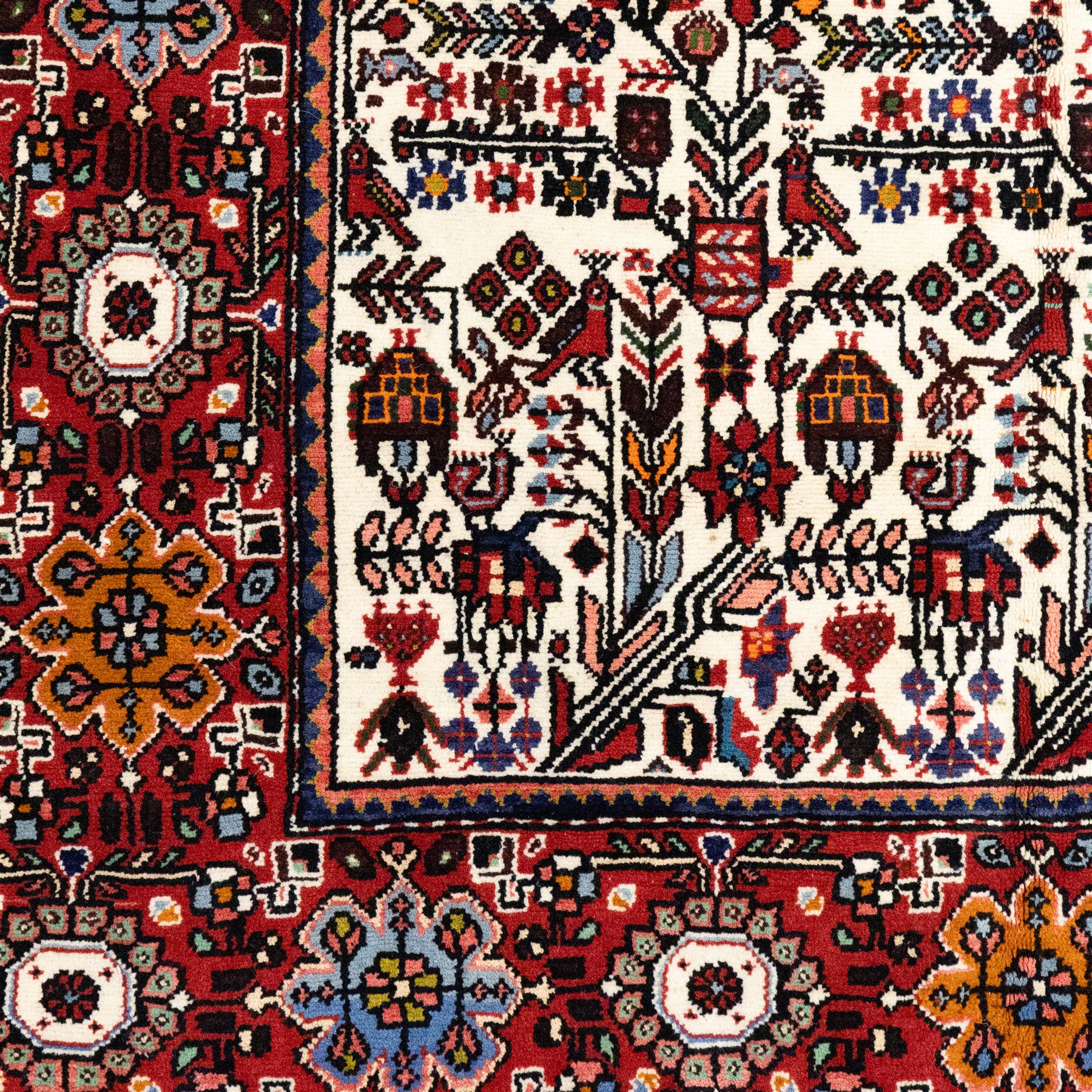 North west Persian Rudbar hand-knotted rug, ivory field woven with a repeating pattern of stylized shrubs, rosettes, and geometric floral motifs in tones of madder red, turquoise, indigo, and ochre, enclosed by a border of linked rosettes and angular flowerheads between narrow guard stripes 