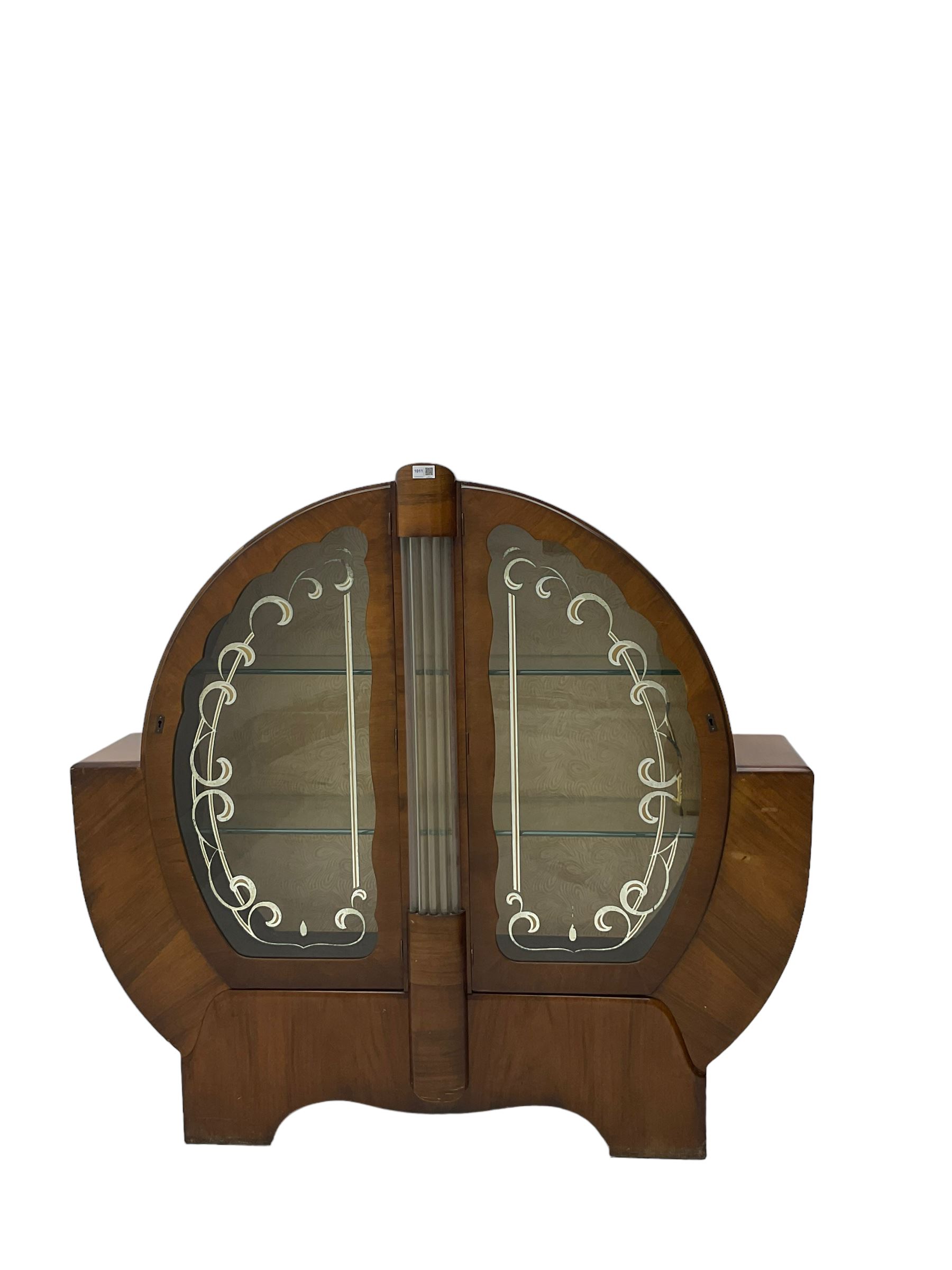 Art Deco walnut display cabinet, of circular design, fitted with two shaped glazed doors enclosing two glass shelves, flanking five glass rods
