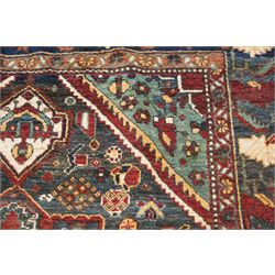 Antique Persian Qashqai dark indigo ground tribal rug, the busy field decorated with a geometric triple pole medallion surrounded by numerous stylised plant motifs with contrasting cyan spandrels, the multiple guard bands woven with stylised palmettes and foliage