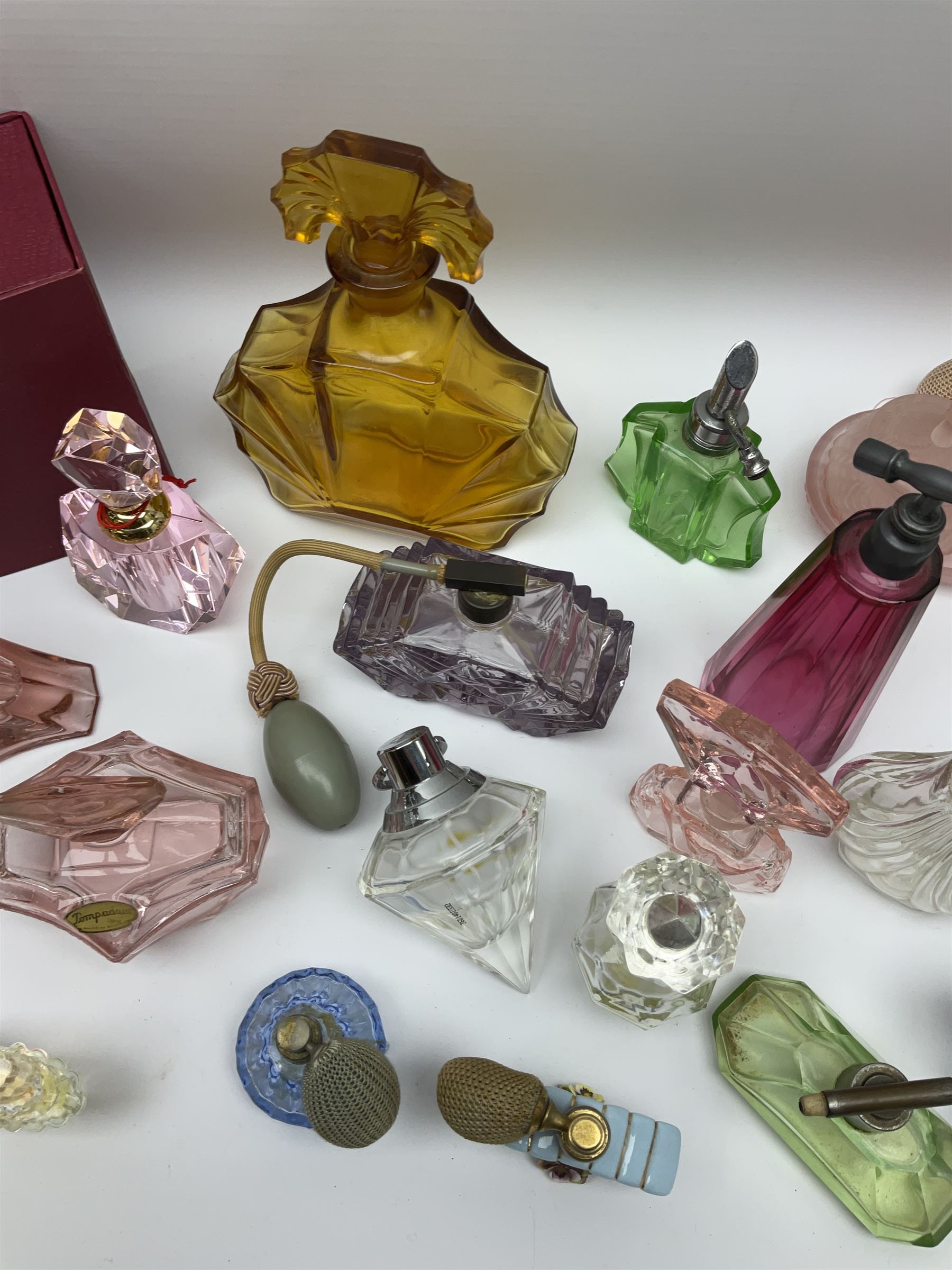 Art Deco style glass perfume bottles and atomisers, to include a large amber example with stopper of fan shape, H18cm, green glass examples with metal stoppers, and a number of other Art Deco style coloured bottles of geometric form with stoppers and mounts