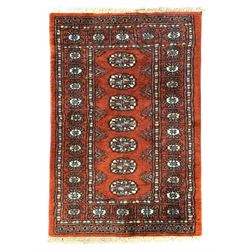 Pair of rugs one Persian hamadan rug central stepped medallion enclosing geometric motifs in ivory and brown, framed by a cream border with scrolling palmettes and fringed ends (H 156cm W 105cm), one Pakistani Bokhara rug rust red ground with repeated Tekke gul motifs within rosette and lozenged borders, fringed ends (H 98cm, W 65cm)