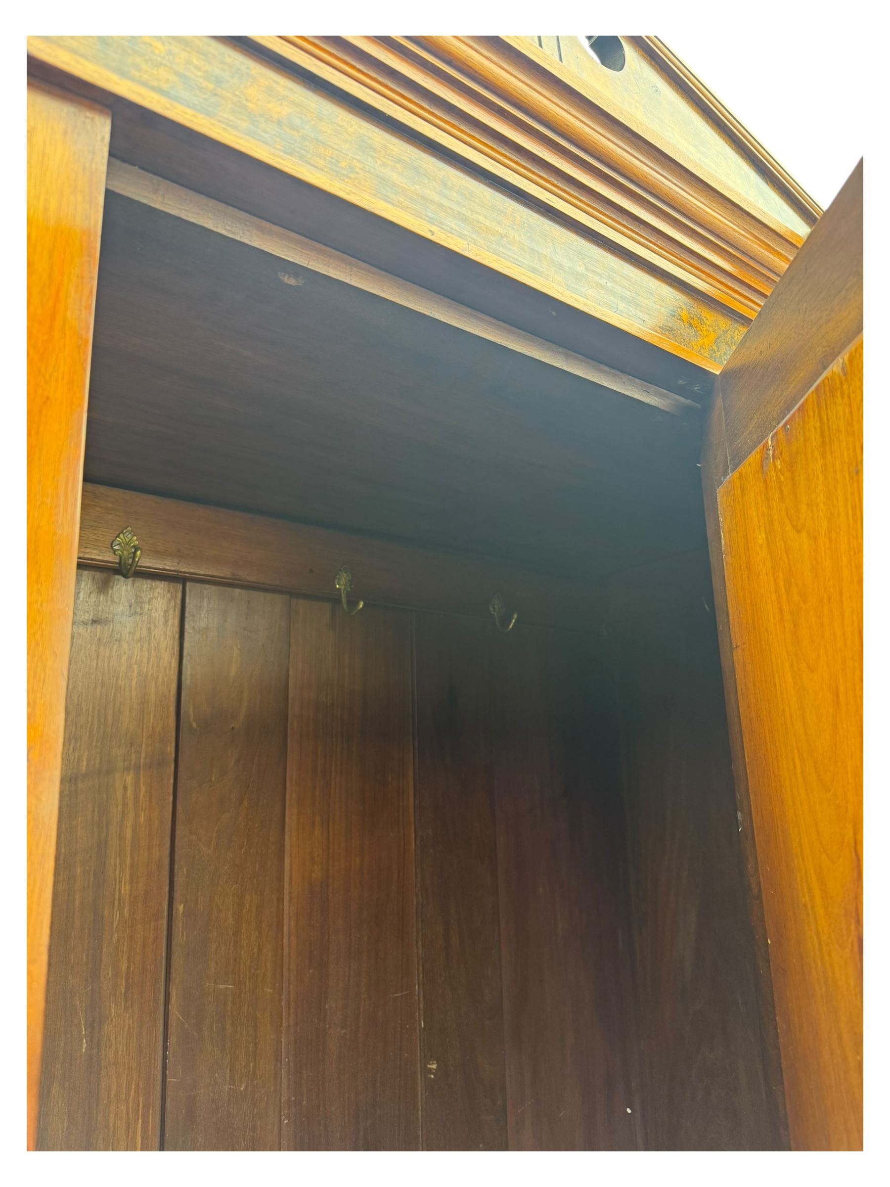 Victorian walnut bedroom suite - wardrobe, dressing chest and bedside cupboard, comprising a full-length wardrobe with broken pediment and central mirrored door, large lower drawer, a matching dressing table with bevelled swing mirror over two trinket drawers and two short drawers over two long drawers, and a single-door bedside cupboard, all with moulded edges, decorative panel work and shaped aprons