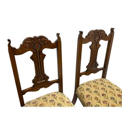 Set four late 19th century carved walnut dining chairs, the shaped cresting rail carved with foliage scrolls, upholstered seats in floral design fabric, square tapering supports with compressed spade feet, on brass and ceramic castors