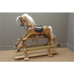  Victorian style wooden rocking horse with stained and dappled carved sectional body, horsehair mane and tail, leather bridle and saddle with iron stirrups, and forward and backward action on stripped pine refectory style base W111cm H102cm  