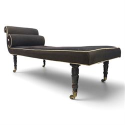 Victorian ebonised chaise longue, upholstered in black fabric with scroll headrest and bolster cushion, rectangular seat with rounded corners, raised on turned supports terminating in brass and ceramic castors