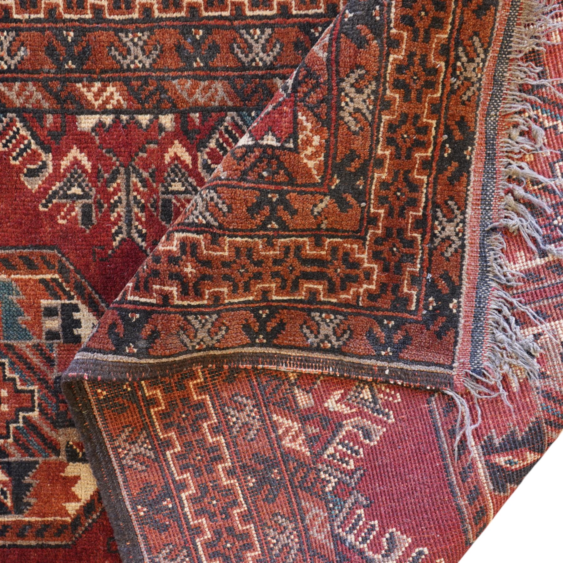 Afghan red ground rug, the field decorated with stylised plant motifs, within multiple borders (137cm x 105cm); together with a Caucasian red ground rug decorated with three Gul motifs (123cm x 85cm)
