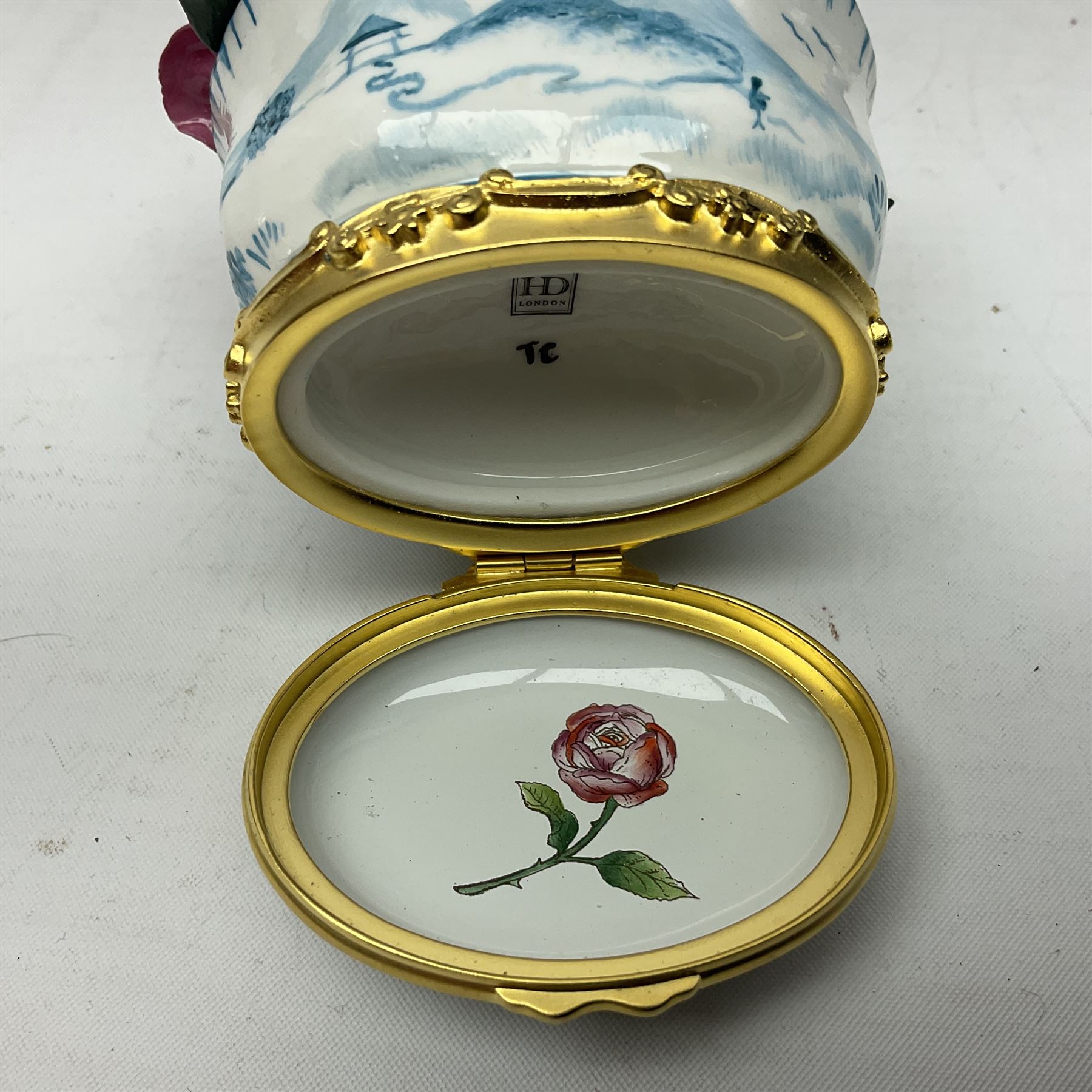 Halcyon Days bonbonniere, modelled as pink roses in a planter painted with a blue and white Japanese scene, together with five Halcyon Days enamel boxes, one a larger example depicting 'The Becket Casket' and four smaller boxes, including The 1993 Easter Egg, Happy Birthday and Statue of Liberty examples, all boxed, Becket Casket D8cm