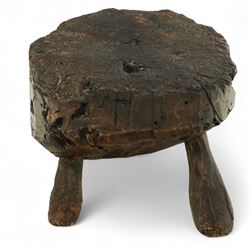 Rustic bog oak stool of oval form with a single solid section with a deeply patinated and textured surface, raised on three tapered stick legs, possibly Irish 
