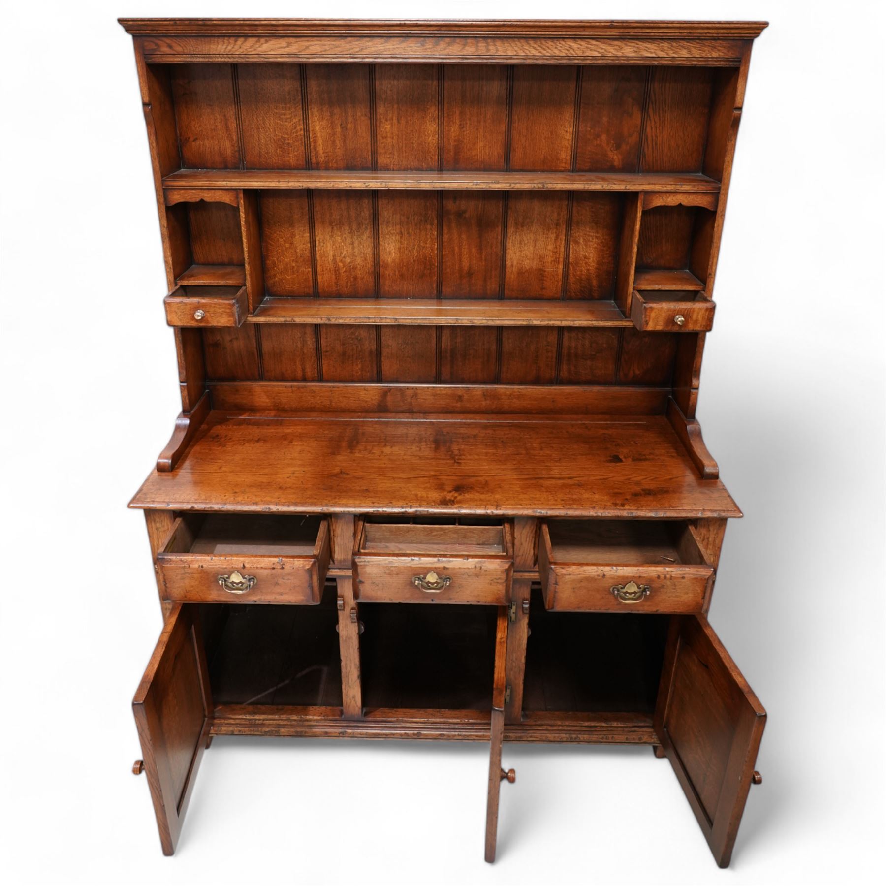 18th century design oak dresser, moulded cornice over two heights plate rack and two small drawers, the dresser base with moulded rectangular top over three drawers and three cupboards, enclosed by ogee arch panelled doors, on stile supports with applied lower moulding