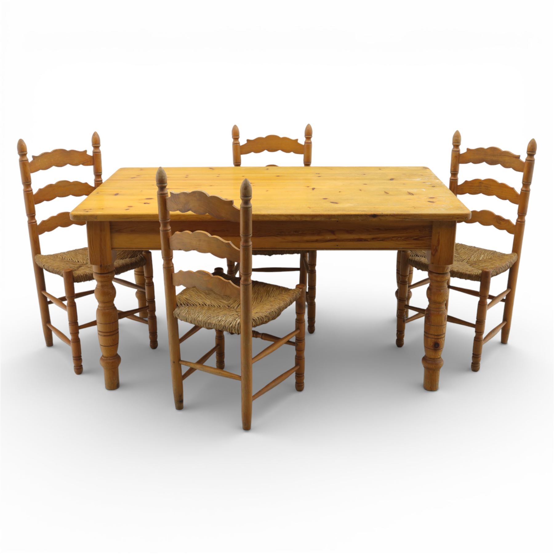 Late 20th century pine farmhouse dining table and four chairs, the rectangular plank top with rounded corners over two frieze drawers fitted with turned knob handles, raised on turned legs, the chairs with shaped ladder backs and turned finials, rush seats in a herringbone weave, on turned supports united by stretchers