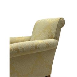Traditionally shaped hardwood-framed armchair, rolled back and arms, upholstered in pale gold and cream damask fabric with repeating foliate pattern, on turned feet with brass cups and castors