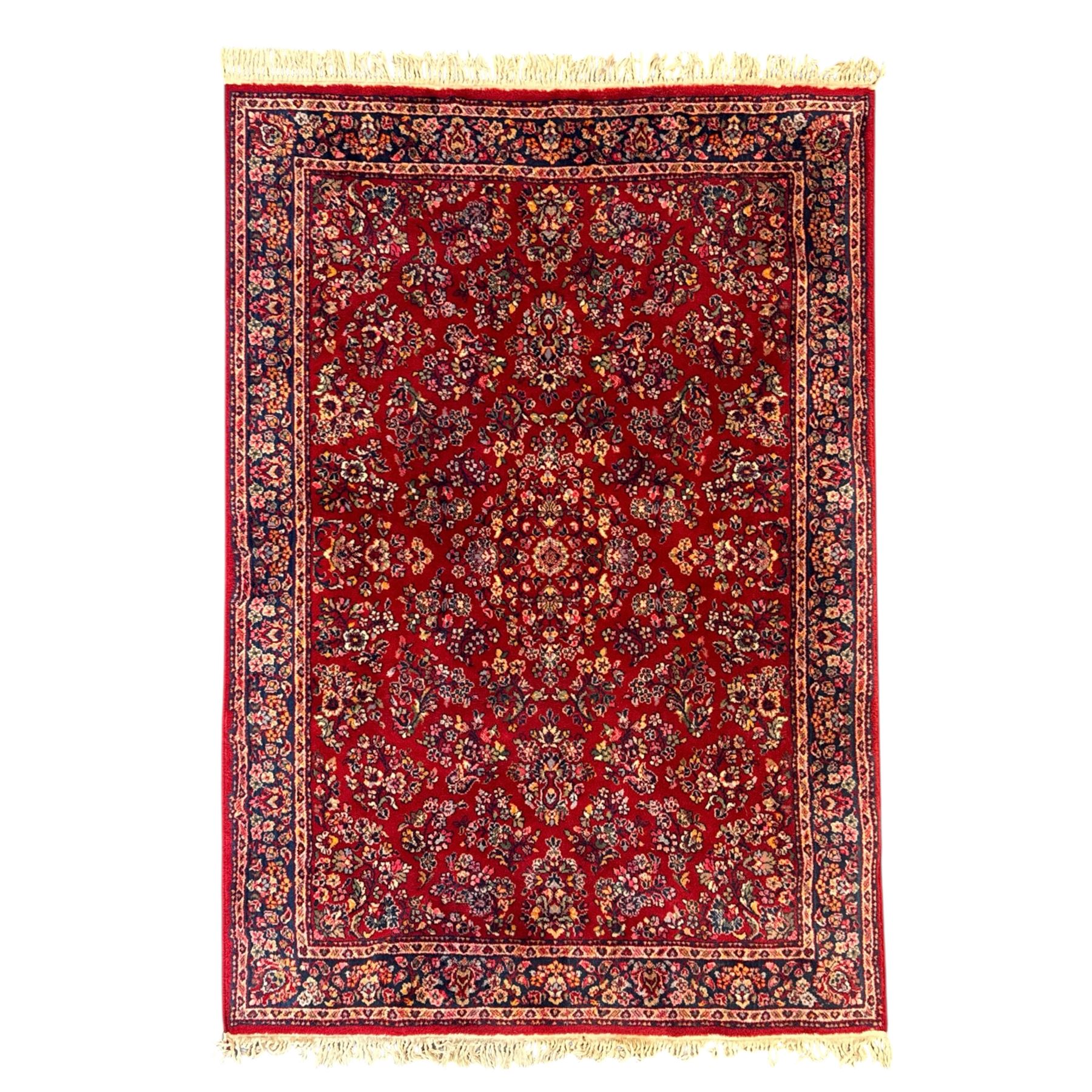 Persian Isfahan-style hand-knotted rug, crimson ground, with an intricated all-over floral spray design with palmettes and leaves, wide midnight blue main border with rosette and palmette motif, flanked by narrow guard borders  